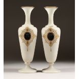 A PAIR OF CAMEO CLASSIC FROSTED VASES with a black cameo with gilt decorations 12ins high.