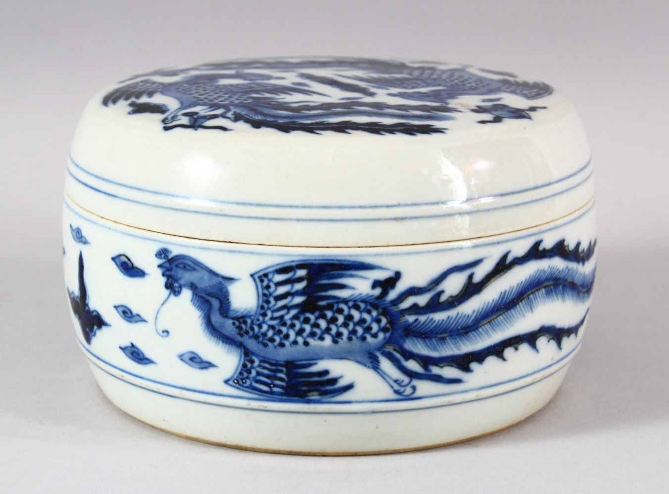 A CHINESE BLUE AND WHITE PORCELAIN CIRCULAR BOX AND COVER, the exterior painted with phoenix, the