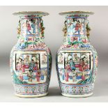 A LARGE PAIR OF CHINESE FAMILLE ROSE TWIN HANDLE VASES, the vases painted with panels depicting