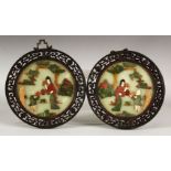 A PAIR OF CHINESE CIRCULAR HARDSTONE PANELS, each depciting figures in a garden, within pierced