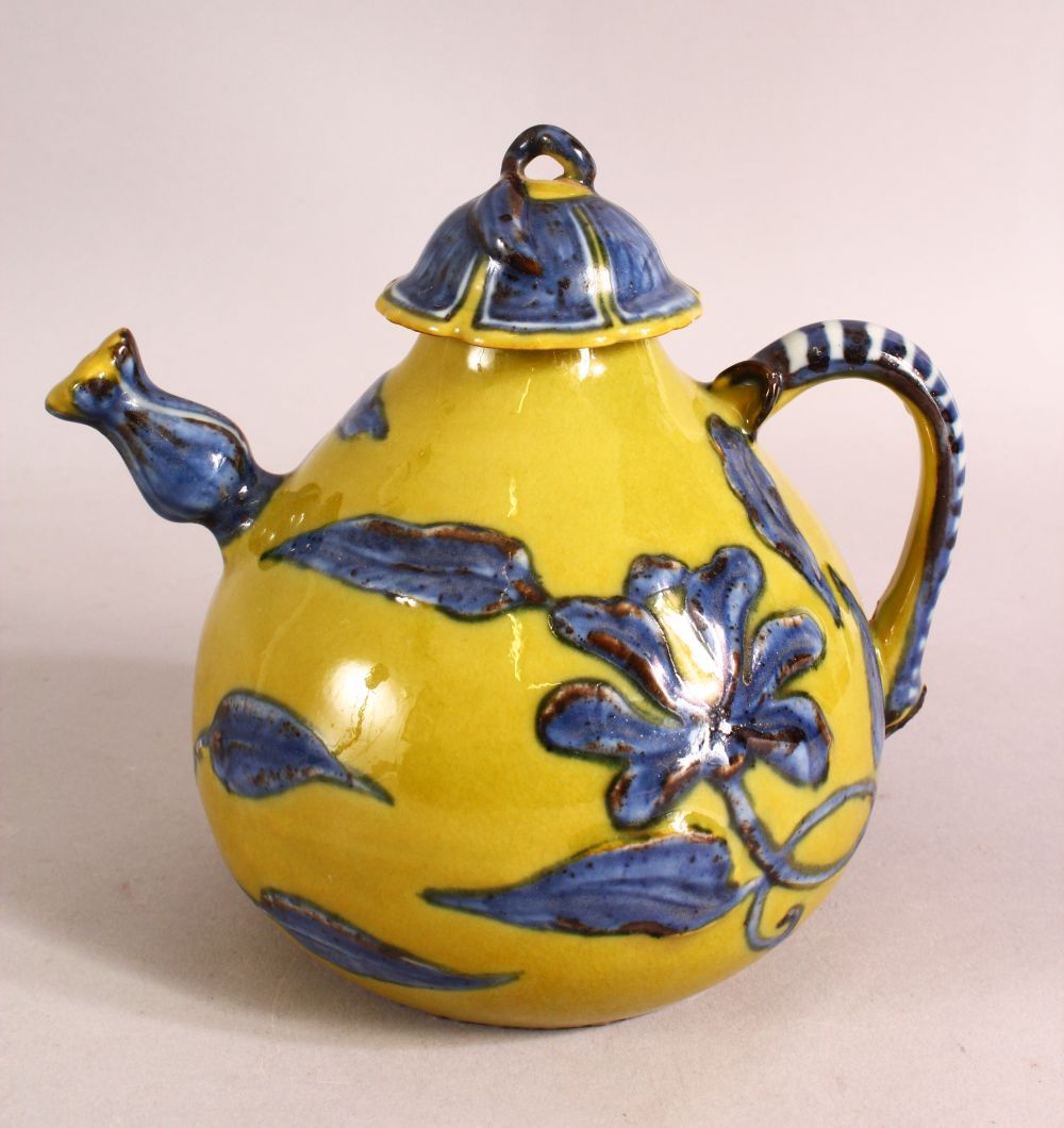 A CHINESE YELLOW GROUND GLAZED POTTERY TEAPOT AND COVER, the body with blue floral decoration,