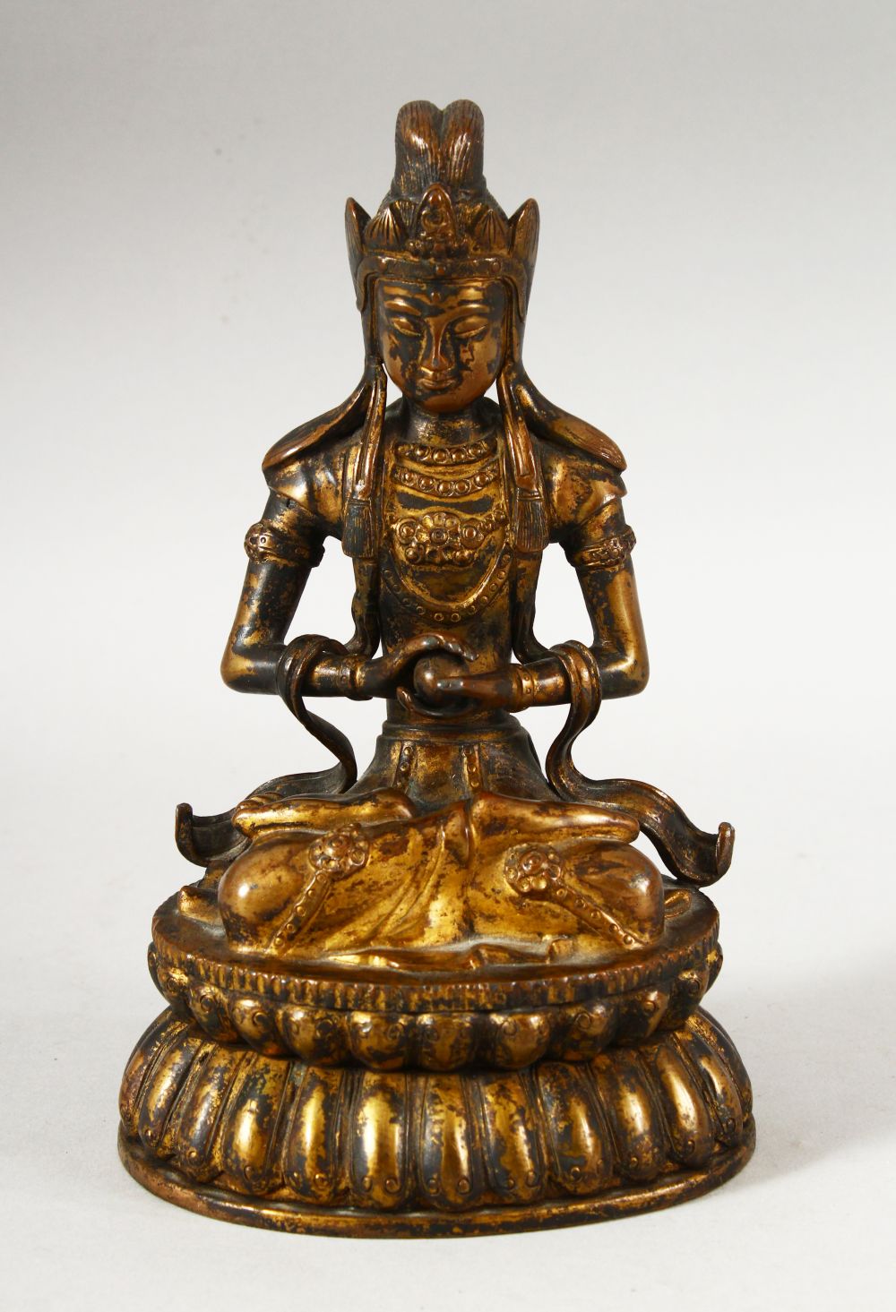 A CHINESE GILT BRONZE FIGURE OF BUDDHA / DEITY - in a seated pose holding a ball, 18cm