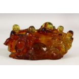 AN AMBER STYLE GROUP OF LAUGHING BUDDHA, surrounded by children, 20cm long.