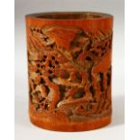 A CHINESE CARVED BAMBOO BRUSH POT, the body carved with landscape scene with figures, 18cm high.