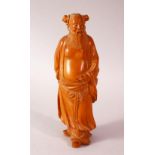 A CHINESE CARVED HARD WOOD FIGURE OF AN IMMORTAL - the figure in traditional gowns with his front