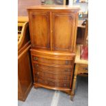 A yew wood narrow chest with a pair of doors over a brushing slide and four long drawers.