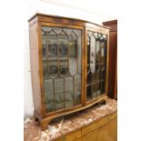 A mahogany serpentine fronted two door display cabinet.