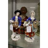 A pair of porcelain figures, one of a boy selling rabbits, the other a girl with a goose under one
