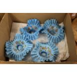 A set of four opaque blue glass frilly edged dishes with floral decoration.