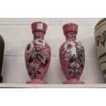 A pair of floral decorated pink opaque glass vases.