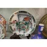 A Chinese Famille Jaune circular plate with figures playing a game.
