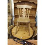 A pine circular kitchen table and three chairs together with a pine oval table top.