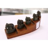 A graduated set of five small bronze elephants on a stepped wood base.