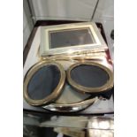 A pair of small silver oval shaped photograph frames and other frames.