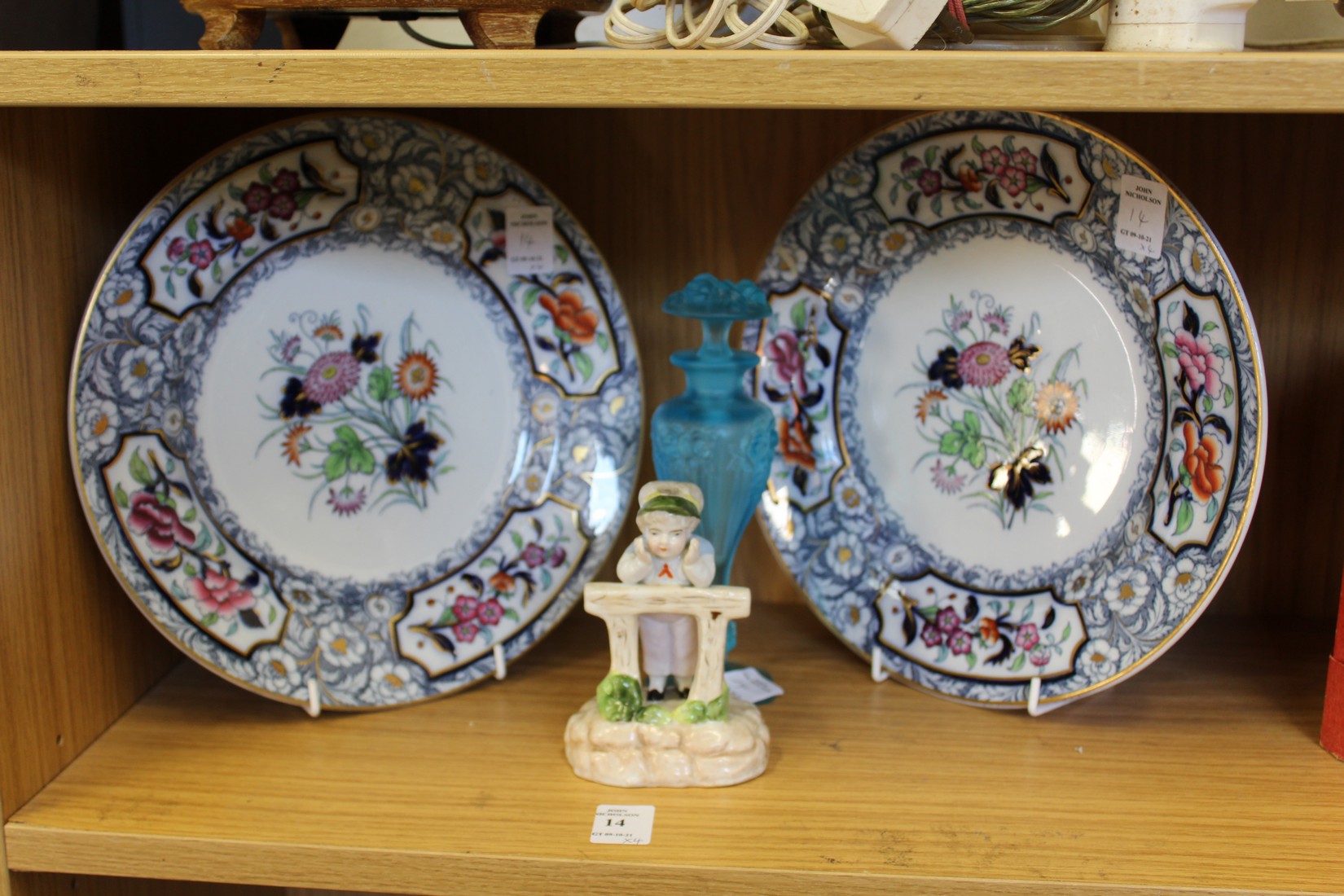 A pair of decorative plates, a porcelain figure and a frosted glass scent bottle.