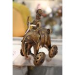 An Indian bronze toy modelled as a man riding a wheeled elephant.