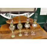 Two pairs of brass and copper oil lamps with cut glass reservoirs.