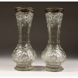 A PAIR OF CUT GLASS VASES with silver tops. 12ins high.