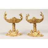 A PAIR OF GILT BRONZE CLASSICAL STYLE PEDESTAL TABLE SALTS. 9ins high x 7ins wide.