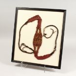 A CHIMU FABRIC SLINGSHOT in red and gold thread, framed and glazed. 18.5ins x 16ins.