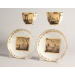 TWO PAIRS OF, POSSIBLY FRENCH, CUPS AND SAUCERS with panels of buildings.