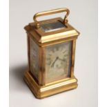 A MINIATURE BRASS CARRIAGE CLOCK with porcelain panel 3ins high.