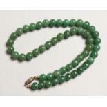 A STRING OF GREEN JADE BEADS