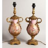 A GOOD PAIR OF 19TH CENTURY FRENCH PORCELAIN AND ORMOLU TWO HANDLED URNS, converted to lamps,