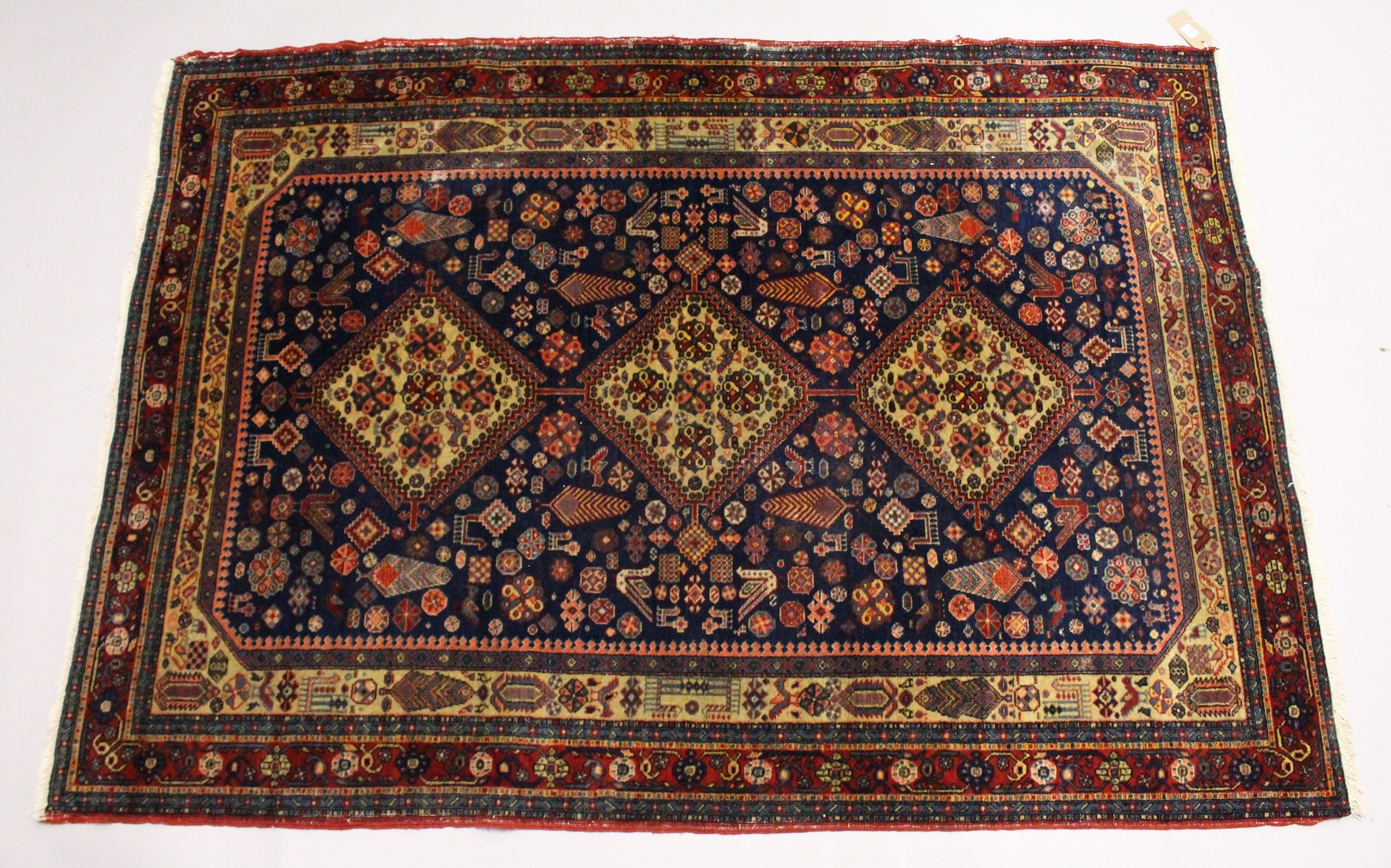 A PERSIAN QUASHQI CARPET, dark blue ground with three central diamond shaped medallions stylised