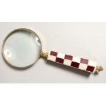 A MAGNIFYING GLASS with chequered handle.