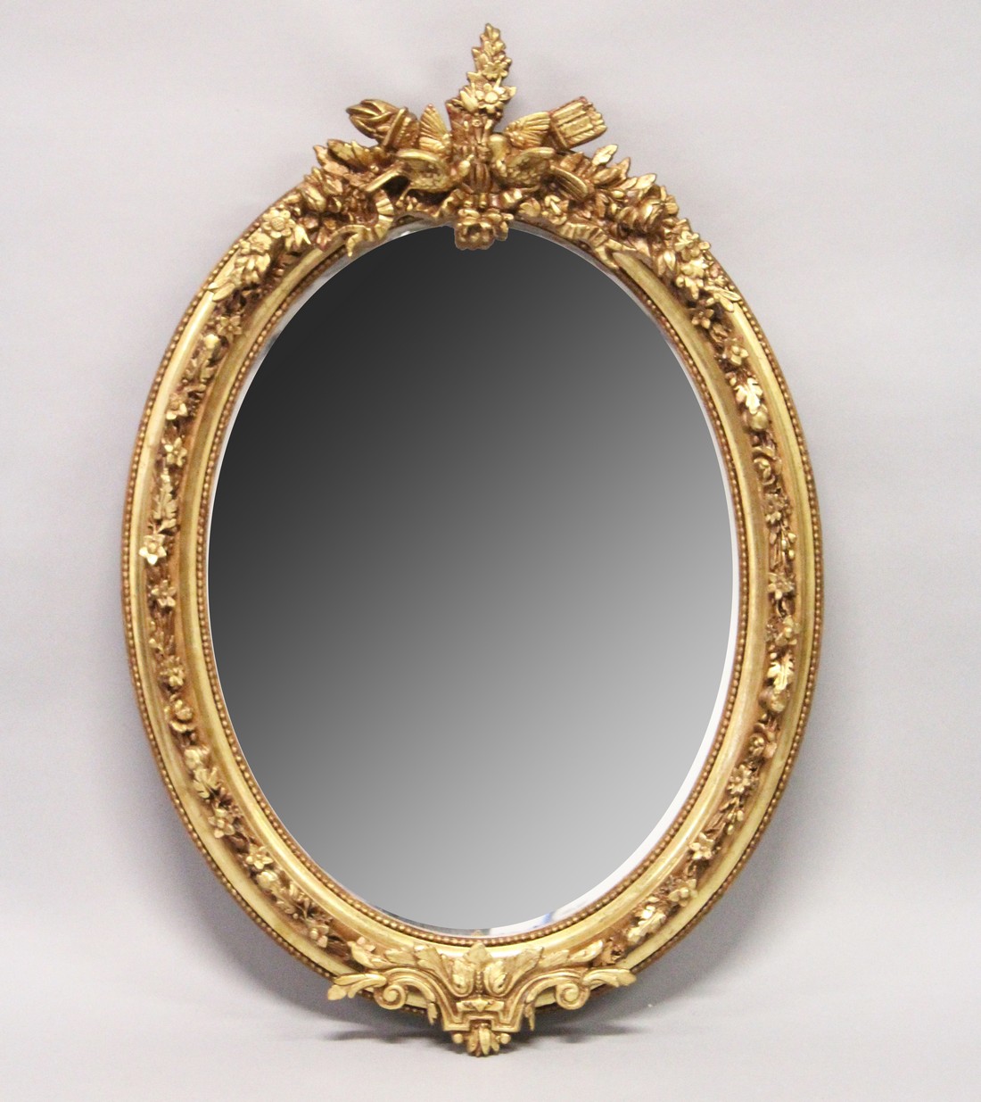 A DECORATIVE GILT FRAMED OVAL WALL MIRROR 3ft 7ins high x 2ft 6ins wide