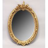 A DECORATIVE GILT FRAMED OVAL WALL MIRROR 3ft 7ins high x 2ft 6ins wide