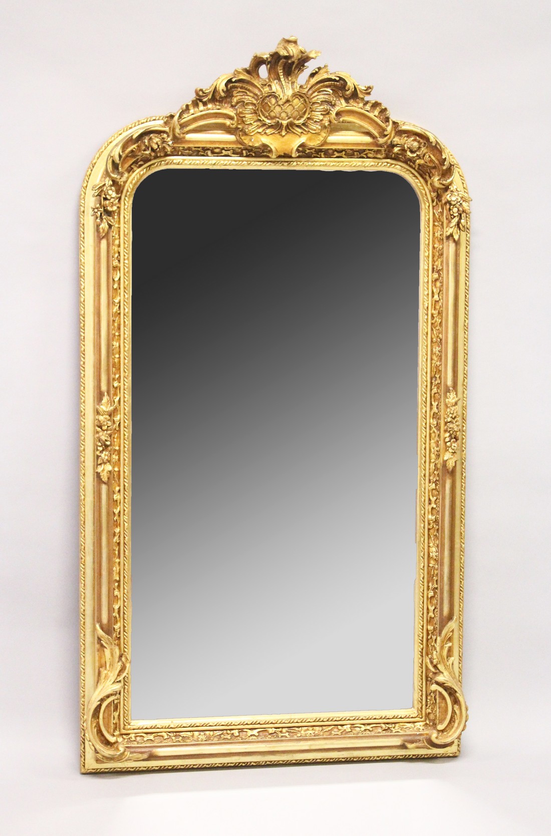 A LARGE ORNATE GILT FRAMED ARCH TOP MIRROR, the top with moulded leafwork decoration. 5ft high x 2ft