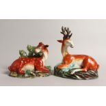 TWO LARGE STAFFORDSHIRE SEATED DEER with spots on rustic bases 7ins & 4.5ins.