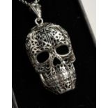 A SILVER FILIGREE SKULL on a chain.