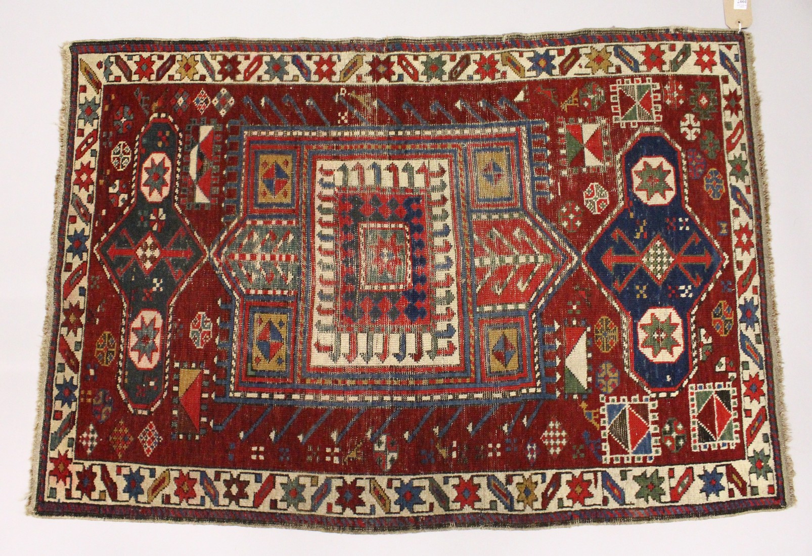 AN UNUSUAL SMALL CAUSASIAN SHIRWAN RUG, claret ground with stylised design. 4ft 2ins x 2ft 10ins