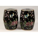 A PAIR OF CHINESE PORCELAIN BARREL SEATS, black ground decorated with birds amongst foliage. 18ins