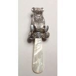 A SILVER TEDDY BEAR AND MOTHER OF PEARL RATTLE.