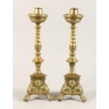 A PAIR OF 17TH CENTURY BRASS CANDLESTICKS on triangular bases 16ins high.