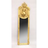 A TALL NARROW GILT FRAMED MIRROR, the upper panel decorated in relief with a female bust. 5ft