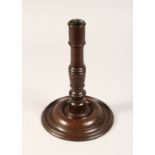 AN 18TH CENTURY TURNED WOOD CANDLESTICK with large circular base 10.5ins high.