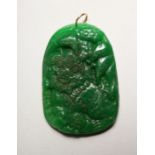 A CHINESE CARVED GREEN JADE PENDANT with gold ring.