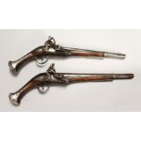 A NEAR PAIR OF EARLY FLINTLOCK PISTOLS with 12 inch engraved barrels, mahogany stock with silver.