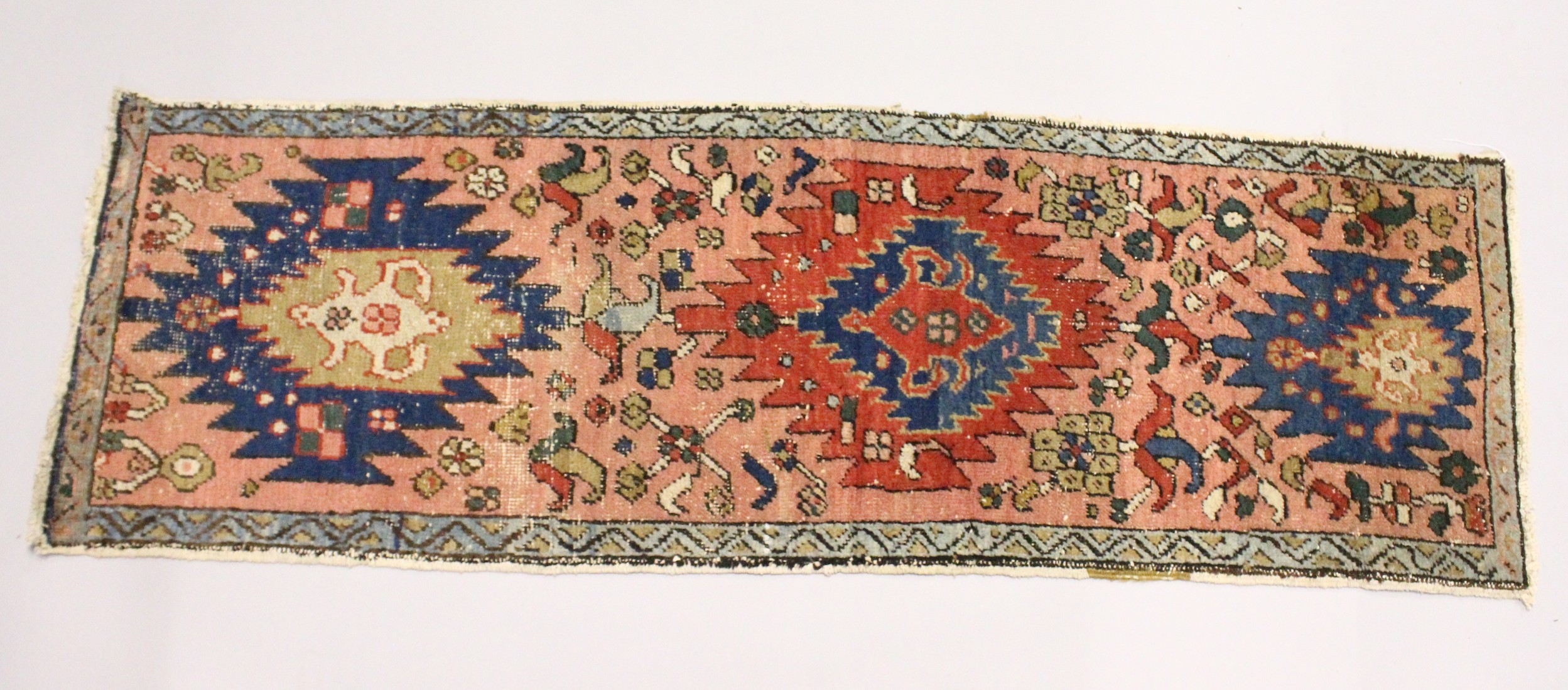 A SMALL HERIZ RUNNER, pink ground with three medallions 5ft 10ins x 1ft 11ins.