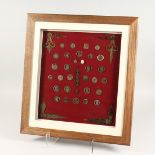 A COLLECTION OF FRAMED COINS, TIE PINS, BUTTONS, MEDALLIONS, AND CLOCK HANDS 17ins x 15in
