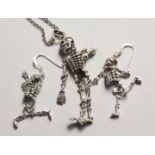 A PAIR OF SILVER ARTICULATED SKELETON EAR RINGS AND NECKLACE on a chain.