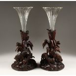 A GOOD PAIR OF BLACK FOREST CARVED WOOD VASE STANDS, one carved as a pair of rabbits, the other a