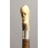 A GOOD 19TH CENTURY WALKING CANE with carved bone handle as a monkey and face, with silver band.