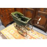 An unusual Victorian pram with wrought iron frame and green leather upholstery.