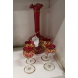 A good cranberry coloured and gilt decorated liqueur set comprising a decanter (lacking stopper) and
